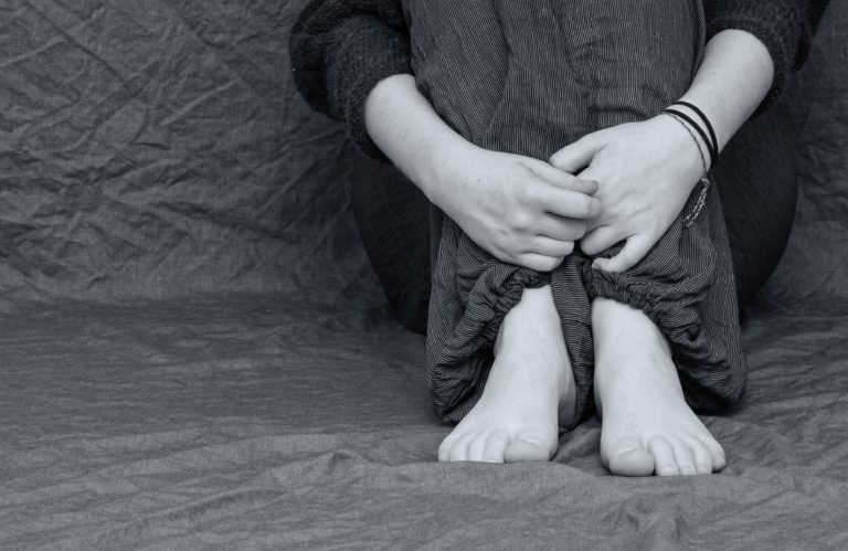A person holding their knees tightly to their body while they are experiencing grief and loss