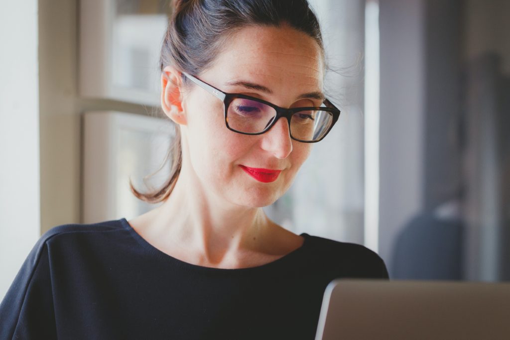 A woman with glasses looking at her computer