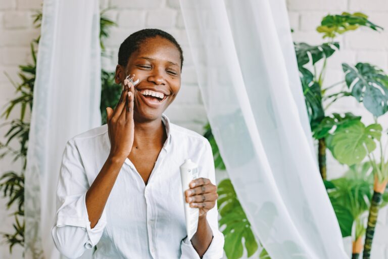 self-care Sunday ideas with a woman smiling and putting lotion on her face